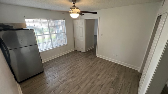 unfurnished dining area featuring a textured ceiling, ceiling fan, and dark wood-type flooring