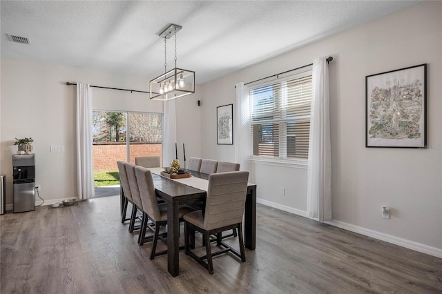 dining room featuring a chandelier, a textured ceiling, and dark hardwood / wood-style floors