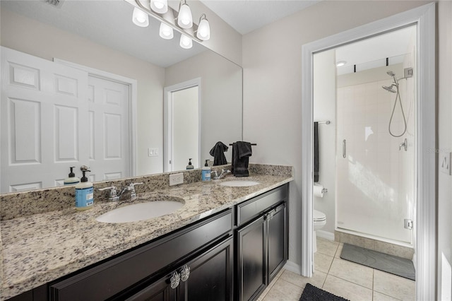 bathroom featuring tile patterned floors, vanity, toilet, and a shower with shower door