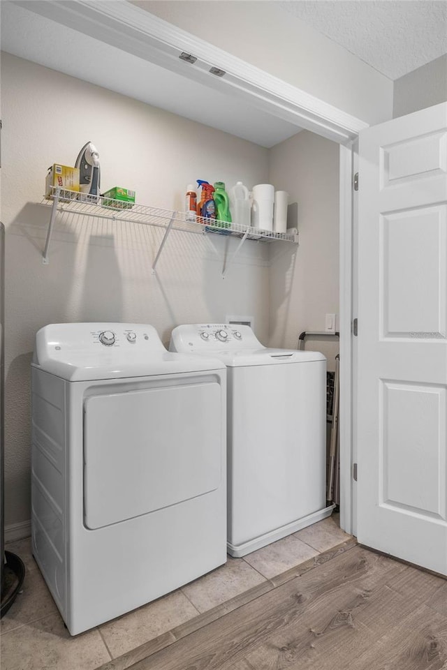 laundry room featuring washer and clothes dryer and light wood-type flooring