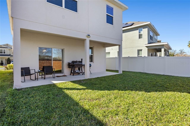 back of house featuring a lawn and a patio area