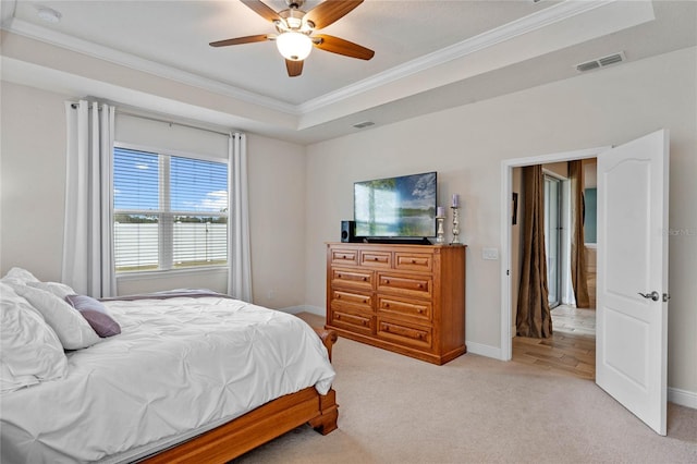 bedroom featuring ornamental molding, light colored carpet, ceiling fan, and a tray ceiling