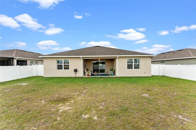 rear view of house featuring ceiling fan, a patio area, and a lawn