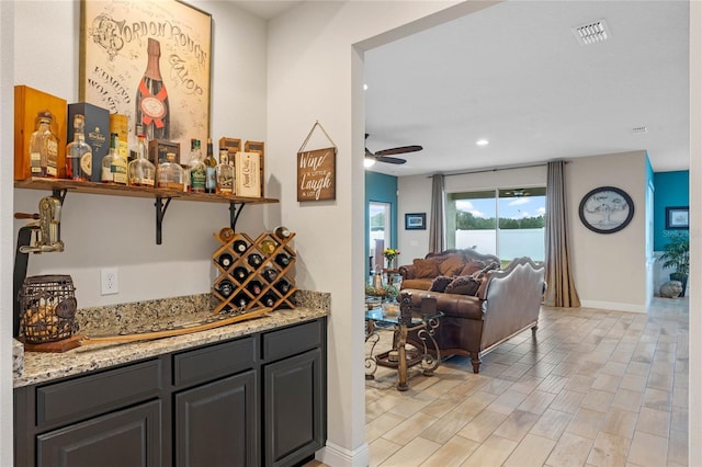 bar with light stone counters and ceiling fan