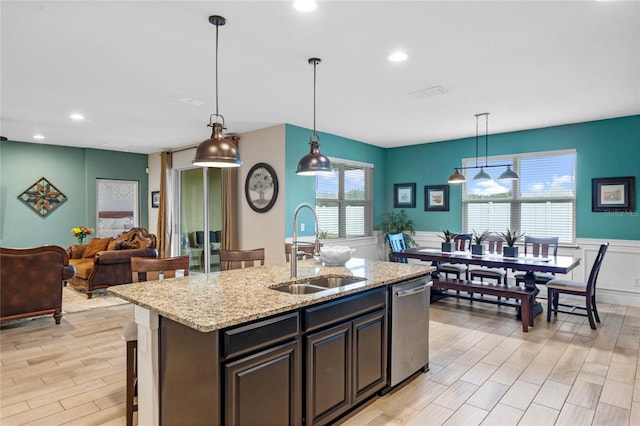 kitchen with a center island with sink, dishwasher, sink, and pendant lighting