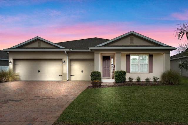 single story home featuring a garage and a lawn