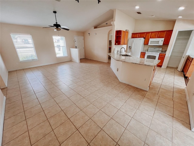 kitchen with light stone countertops, white appliances, sink, light tile patterned floors, and lofted ceiling