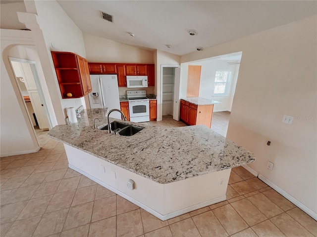 kitchen with kitchen peninsula, light stone counters, white appliances, sink, and lofted ceiling