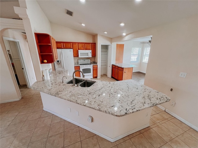 kitchen with ceiling fan, sink, light stone counters, white appliances, and a kitchen island