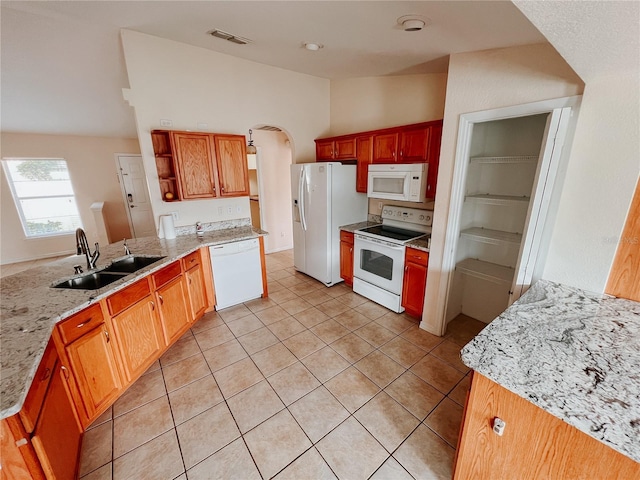 kitchen with sink, light stone counters, kitchen peninsula, white appliances, and light tile patterned floors