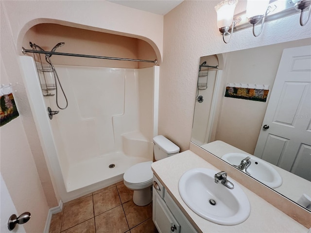 bathroom with a shower, tile patterned flooring, vanity, and toilet