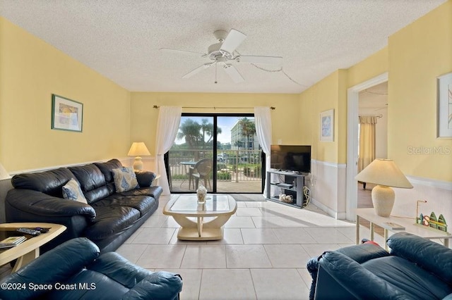 living room with ceiling fan, light tile patterned floors, and a textured ceiling