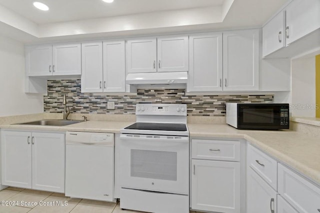 kitchen featuring tasteful backsplash, white appliances, sink, light tile patterned floors, and white cabinets