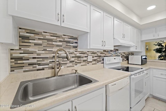 kitchen with tasteful backsplash, white cabinetry, sink, and white appliances