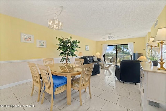 dining space with ceiling fan with notable chandelier, light tile patterned floors, and a textured ceiling