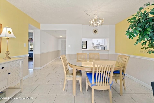 tiled dining area featuring a chandelier and a textured ceiling