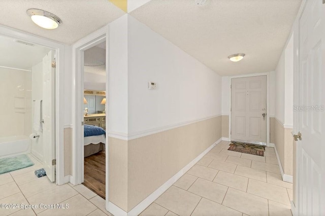 corridor with light tile patterned floors and a textured ceiling