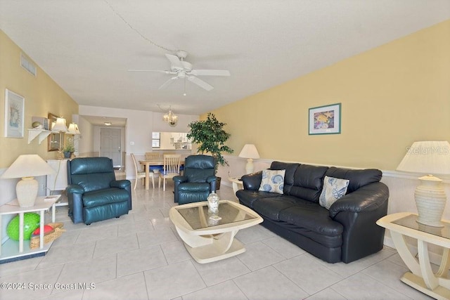 tiled living room featuring ceiling fan with notable chandelier