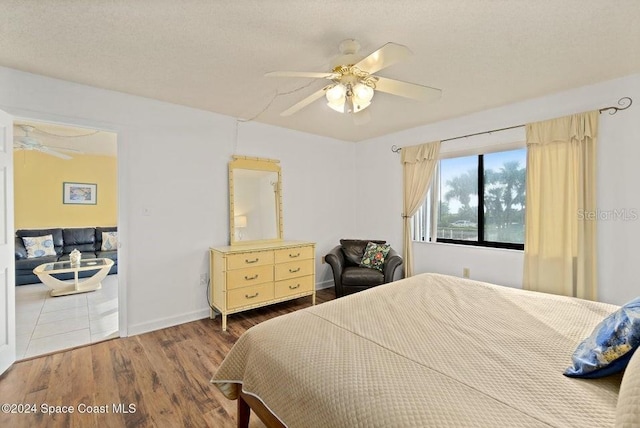 bedroom featuring ceiling fan, hardwood / wood-style floors, and a textured ceiling