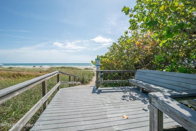 wooden terrace featuring a water view and a beach view