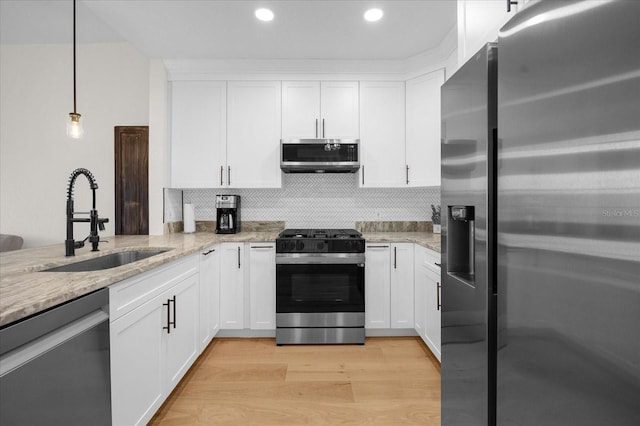 kitchen featuring decorative light fixtures, white cabinetry, sink, and appliances with stainless steel finishes