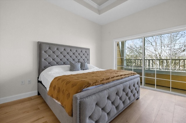 bedroom with access to outside, hardwood / wood-style flooring, a raised ceiling, and ornamental molding