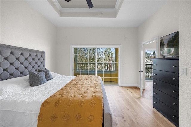 bedroom with light wood-type flooring, a raised ceiling, ceiling fan, and crown molding