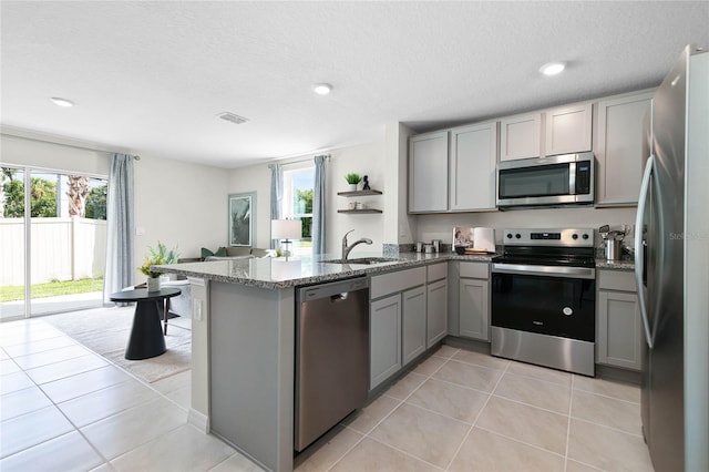 kitchen featuring stainless steel appliances, sink, stone counters, gray cabinets, and light tile patterned flooring