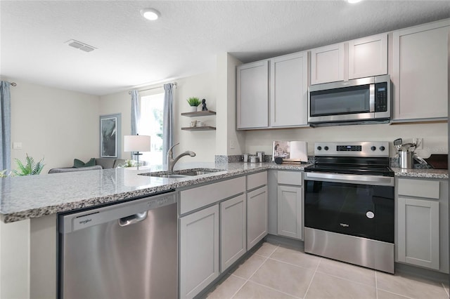 kitchen featuring kitchen peninsula, a textured ceiling, stainless steel appliances, sink, and light tile patterned floors