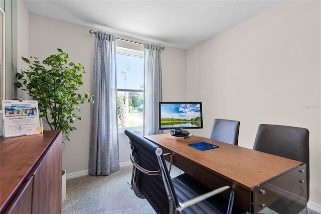 carpeted home office with a textured ceiling and a wealth of natural light