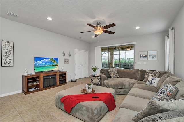 living room with tile patterned floors, ceiling fan, and a textured ceiling