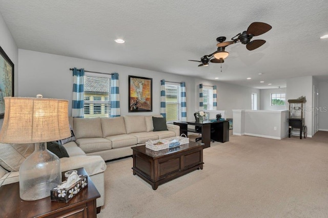 living room with a textured ceiling, ceiling fan, and light carpet