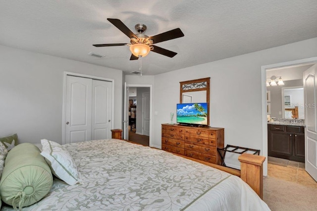 bedroom featuring ceiling fan, ensuite bath, a textured ceiling, and a closet