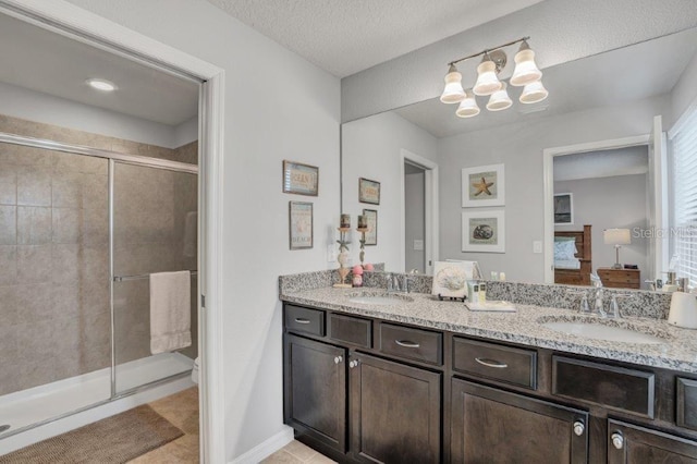 bathroom featuring tile patterned flooring, vanity, a shower with shower door, and a textured ceiling