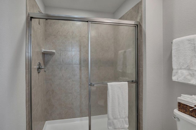 bathroom featuring a shower with shower door and toilet