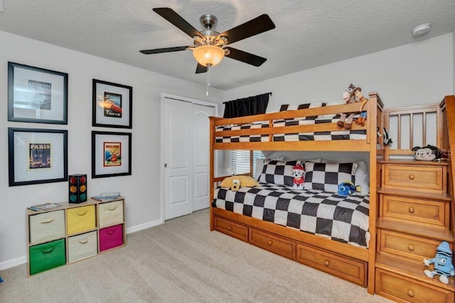 bedroom featuring ceiling fan, a textured ceiling, light carpet, and a closet