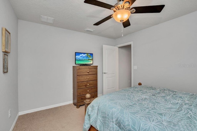 carpeted bedroom featuring ceiling fan and a textured ceiling