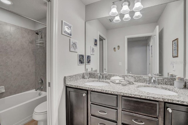 full bathroom featuring vanity, tiled shower / bath combo, and toilet