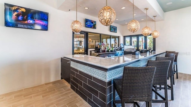 bar with light stone countertops and hanging light fixtures