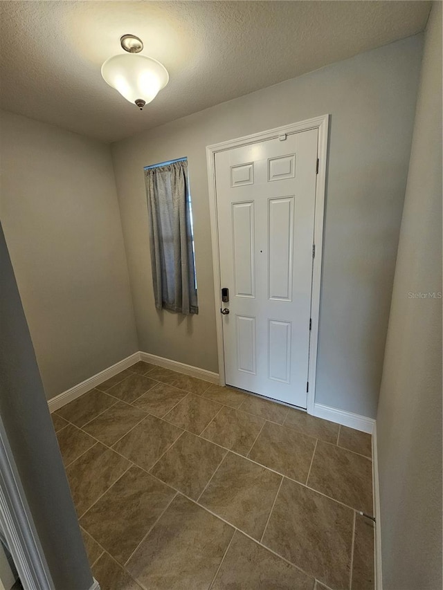 entryway with dark tile patterned floors and a textured ceiling