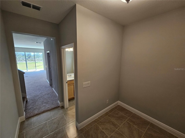 hallway featuring a textured ceiling and dark tile patterned floors