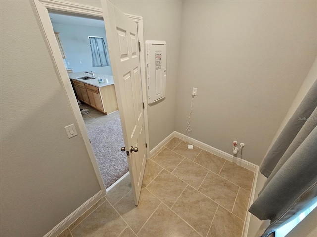 laundry room featuring sink, light tile patterned floors, and electric panel