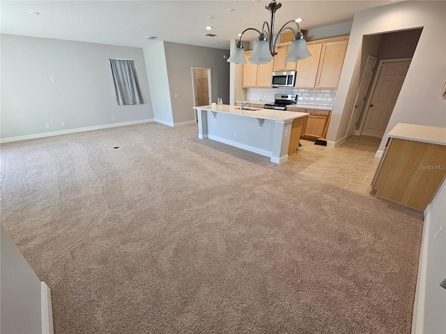 kitchen with light brown cabinets, decorative backsplash, hanging light fixtures, stainless steel appliances, and a center island with sink