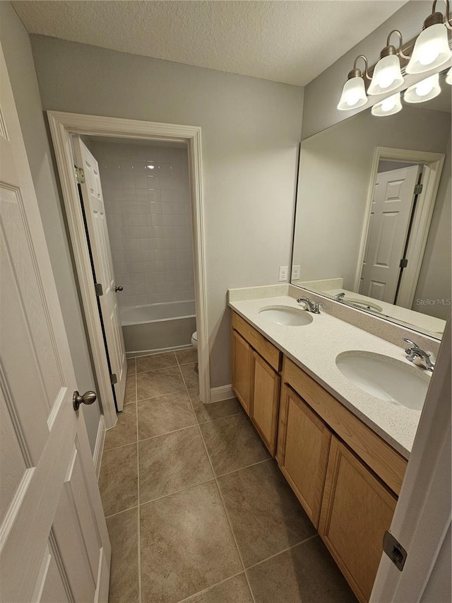 full bathroom with tile patterned floors, toilet, tiled shower / bath, a textured ceiling, and vanity