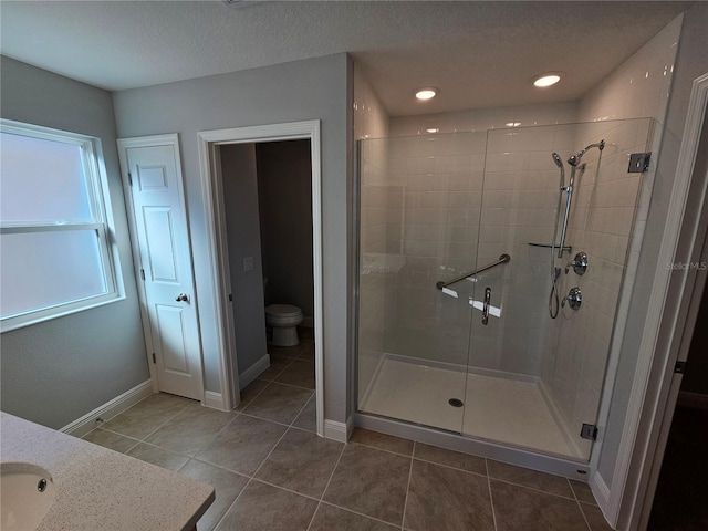 bathroom featuring an enclosed shower, vanity, a textured ceiling, tile patterned floors, and toilet