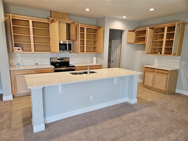 kitchen with a breakfast bar, sink, appliances with stainless steel finishes, light colored carpet, and a kitchen island with sink