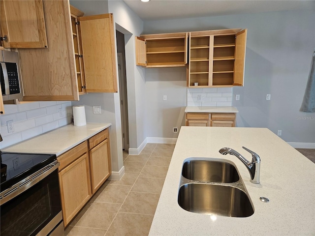 kitchen with tasteful backsplash, sink, light tile patterned floors, and appliances with stainless steel finishes