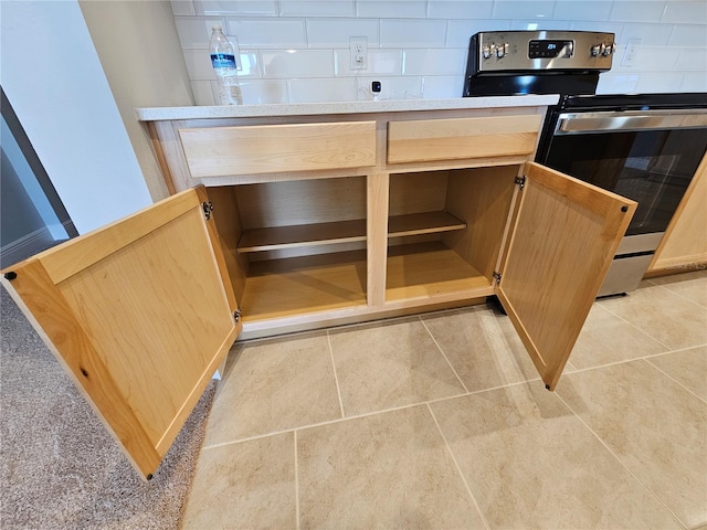 interior details with backsplash, electric range, and light brown cabinets