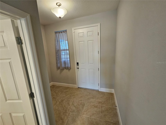 doorway to outside with light tile patterned floors and a textured ceiling