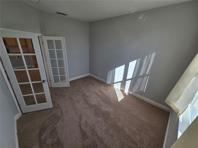 carpeted spare room featuring french doors